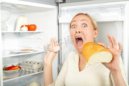 一个饥饿的金发女郎在冰箱前投降