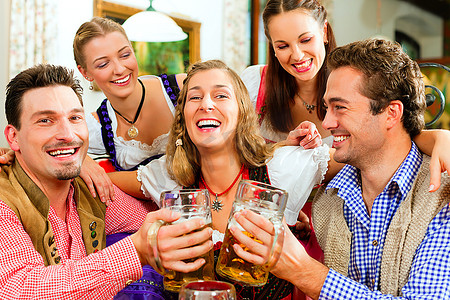 巴伐利亚州的客栈或酒吧--五名年轻男女在传统的Tracht喝着啤酒，开着啤酒聚会