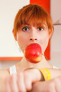 一名妇女被卷尺铐住，并被苹果标志堵住了嘴，这是饮食失调的标志