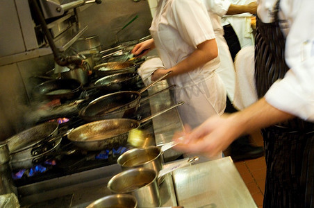 餐厅厨房的工作人员在炉子旁忙碌着工作。