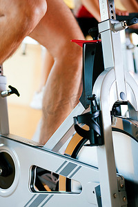 纺丝摄影照片_三个人在健身房里旋转，锻炼他们的腿和心脏训练，只看到四肢和轮子