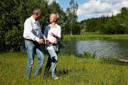 在岸边草地上流淌的湖边，成熟的或年长的夫妇靠得很近