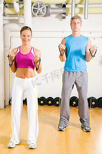 耐久摄影照片_非常健康的一对夫妇在健身房锻炼，带着管状器械做力量体操
