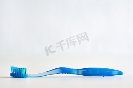 牙刷不干胶摄影照片_单蓝色牙刷躺在面对了一个白色背景。