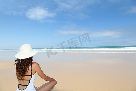 海滩美女摄影照片_戴着草帽坐在海滩上的美女