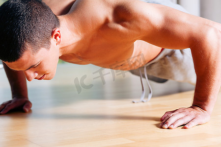 强壮，英俊的人做俯卧撑在健身房作为健美运动，训练他的肌肉