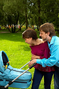 一对已婚夫妇推着婴儿车在公园散步