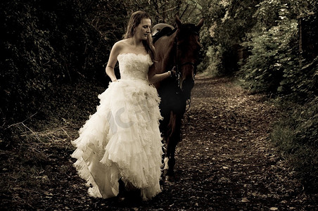 马上开战摄影照片_穿着婚纱的女人骑在马上。