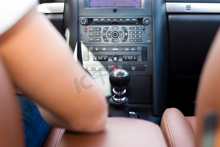 小司机摄影照片_司机正坐在他的汽车或面包车里，正在驾驶-专注于中控台
