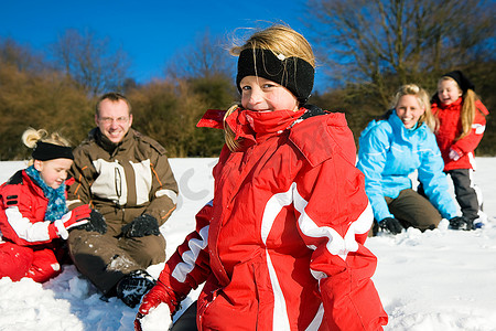 冬天，一家人带着孩子在雪地里的山顶上打雪仗