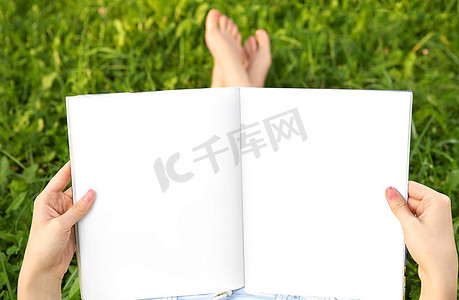 展开的书摄影照片_空荡荡的在女性的手脚和夏日的草地上蔓延