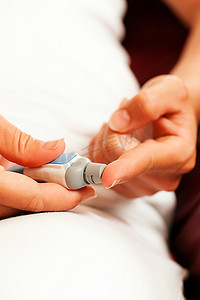 测试仪表摄影照片_一名妇女从手指上采集血样进行血糖水平测试，以显示她是否患有糖尿病