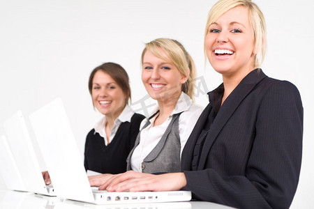 计算机组成摄影照片_一个由三个快乐的年轻女商人组成的团队在笔记本电脑上工作