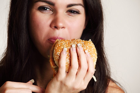 女性在白色背景下吃孤立的汉堡