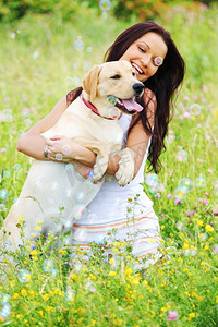 女人和她在绿色的草地上拉布拉多狗