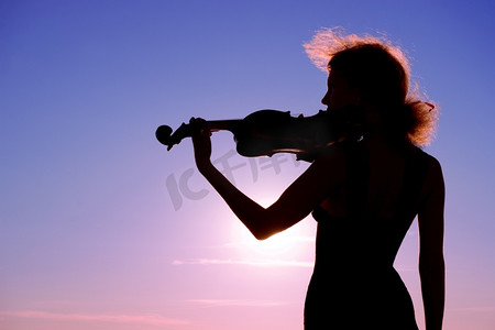 小提琴演奏者在日落时表演独奏