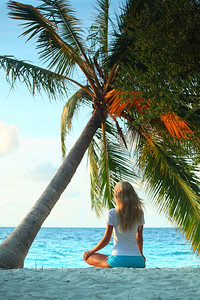 海边棕榈树下的瑜伽女子