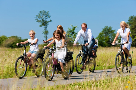 夏天，一家人带着孩子和三个女孩骑着自行车在美丽的风景中进行周末短途旅行