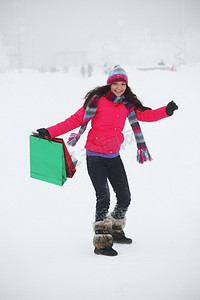 代金券礼包摄影照片_雪地上拿着礼包的冬日女孩