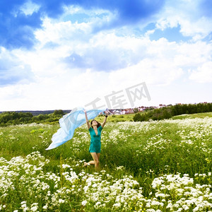 女孩在田野中奔跑，手中的布料像翅膀一样在后面飞翔