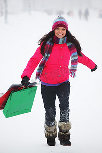 游戏礼包盒摄影照片_雪地上拿着礼包的冬日女孩