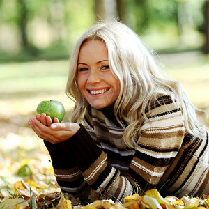 秋摄影照片_秋天公园里戴着青苹果的女人