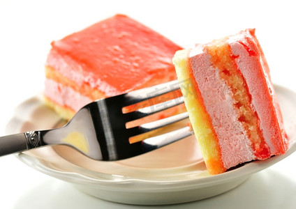 红色叉摄影照片_草莓味的层状蛋糕放在叉子上