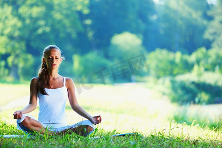 年轻女子做瑜伽运动在绿色公园