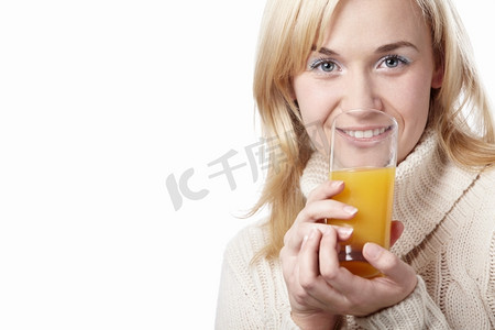 一名穿着毛衣的女子在白色背景上喝果汁