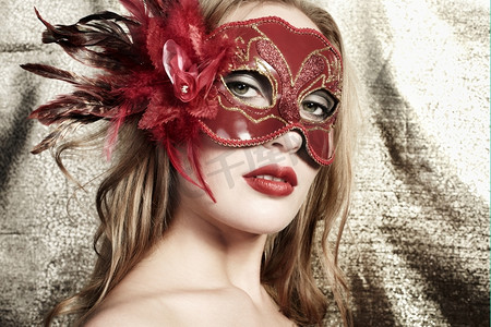 金色背景下戴着神秘的红色威尼斯面具的年轻漂亮女子