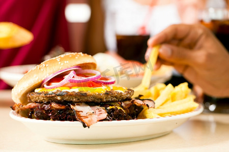 一道菜摄影照片_快餐汉堡包和薯条在餐馆里放在一道菜上-特写并专注于汉堡
