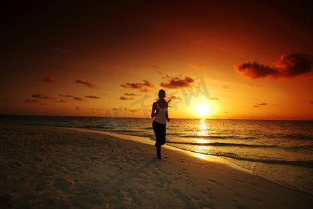 海边女子摄影照片_一名女子沿着日出后的海边奔跑