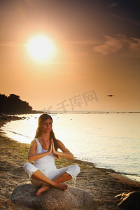 妇女的剪影在瑜伽莲花冥想位置前面到海边
