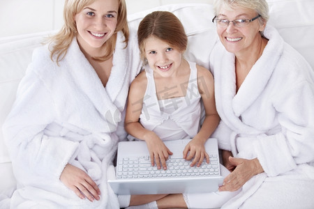三名不同年龄的女性手持笔记本电脑