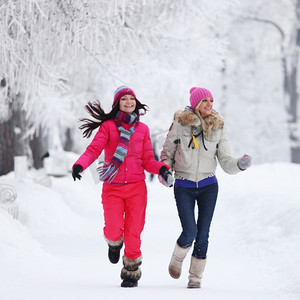 两名冬季妇女在白雪覆盖的小巷中奔跑