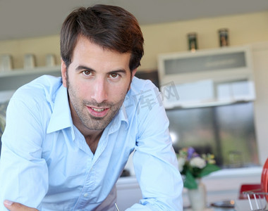 拉丁文摄影照片_微笑的男人站在家里的厨房里