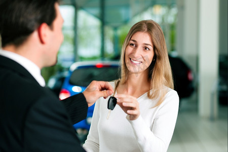 一个女人在汽车经销商那里买车，销售代表给了她钥匙。