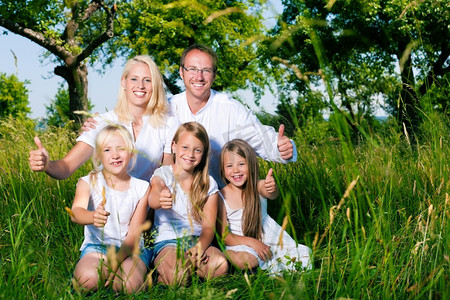 夏天和女儿们坐在草地上的幸福家庭