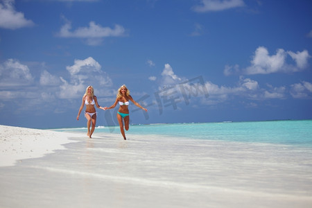 海滩奔跑的美摄影照片_两个女孩沿着海边奔跑