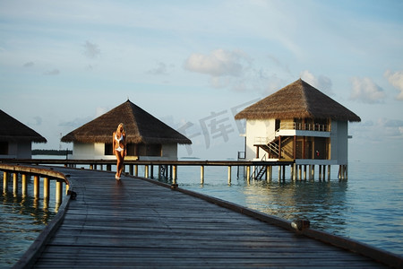 女人穿着裙子站在桥上回家的大海,背景是马尔代夫的日落海洋桥梁