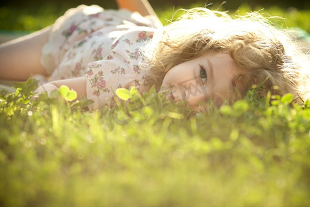 阳光下，一个漂亮的孩子躺在春天的草地上