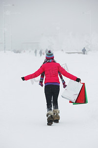 ui礼包简约摄影照片_雪地上拿着礼包的冬日女孩