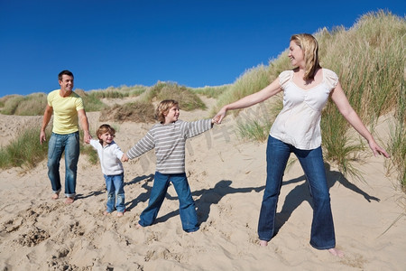两人牵手摄影照片_母亲，父亲和两个男孩在海滩上牵手