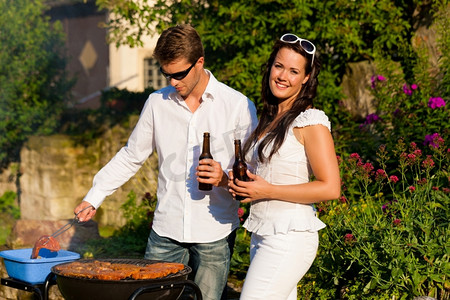喝酒吃肉摄影照片_夫妻--男人和女人--夏天在他们的花园里一起烧烤