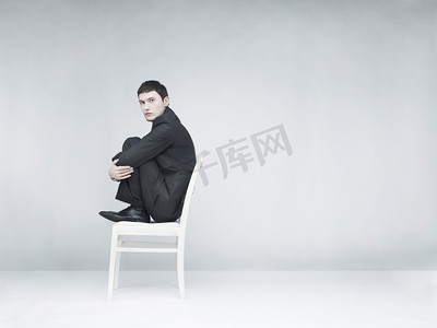 激励措施摄影照片_一个男人坐在白色凳子上的超现实主义肖像