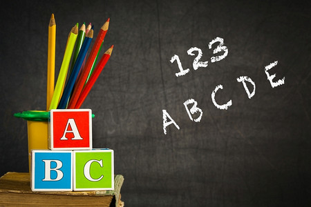 课堂上用ABC和彩色铅笔对着黑板上的旧书。学校理念