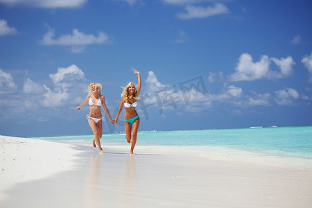 两个女孩沿着海边奔跑