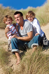 男人和两个男孩，父子俩在海滩玩得开心