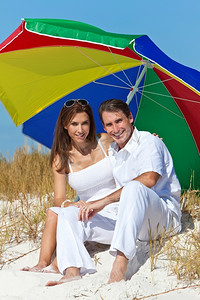 沙滩衣服摄影照片_沙滩上彩伞下的男女情侣