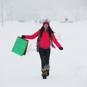 礼包摄影照片_雪地上拿着礼包的冬日女孩